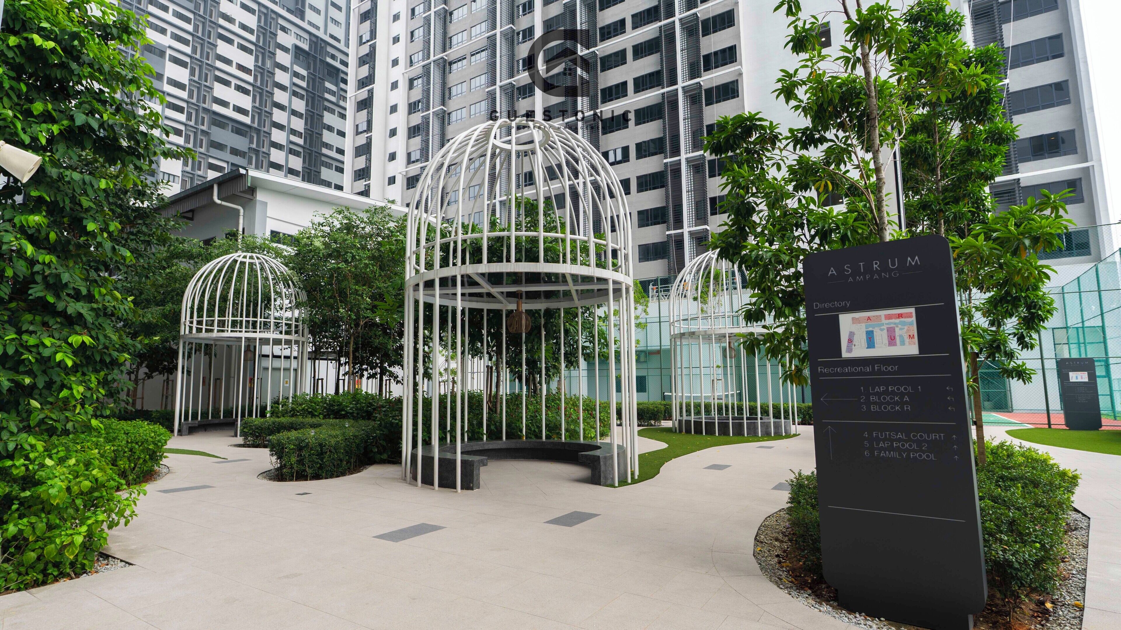 A modern building with a glass facade, surrounded by greenery and featuring two white, dome-shaped structures.