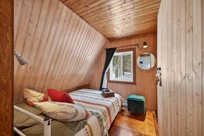 A wooden cabin bedroom with a bunk bed, a small table, a mirror, and a window with curtains. - La Petite Echappee - spa (Orford)