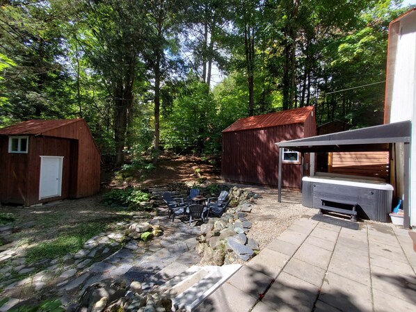 A rustic outdoor area with wooden sheds, stone pathways, and outdoor seating.