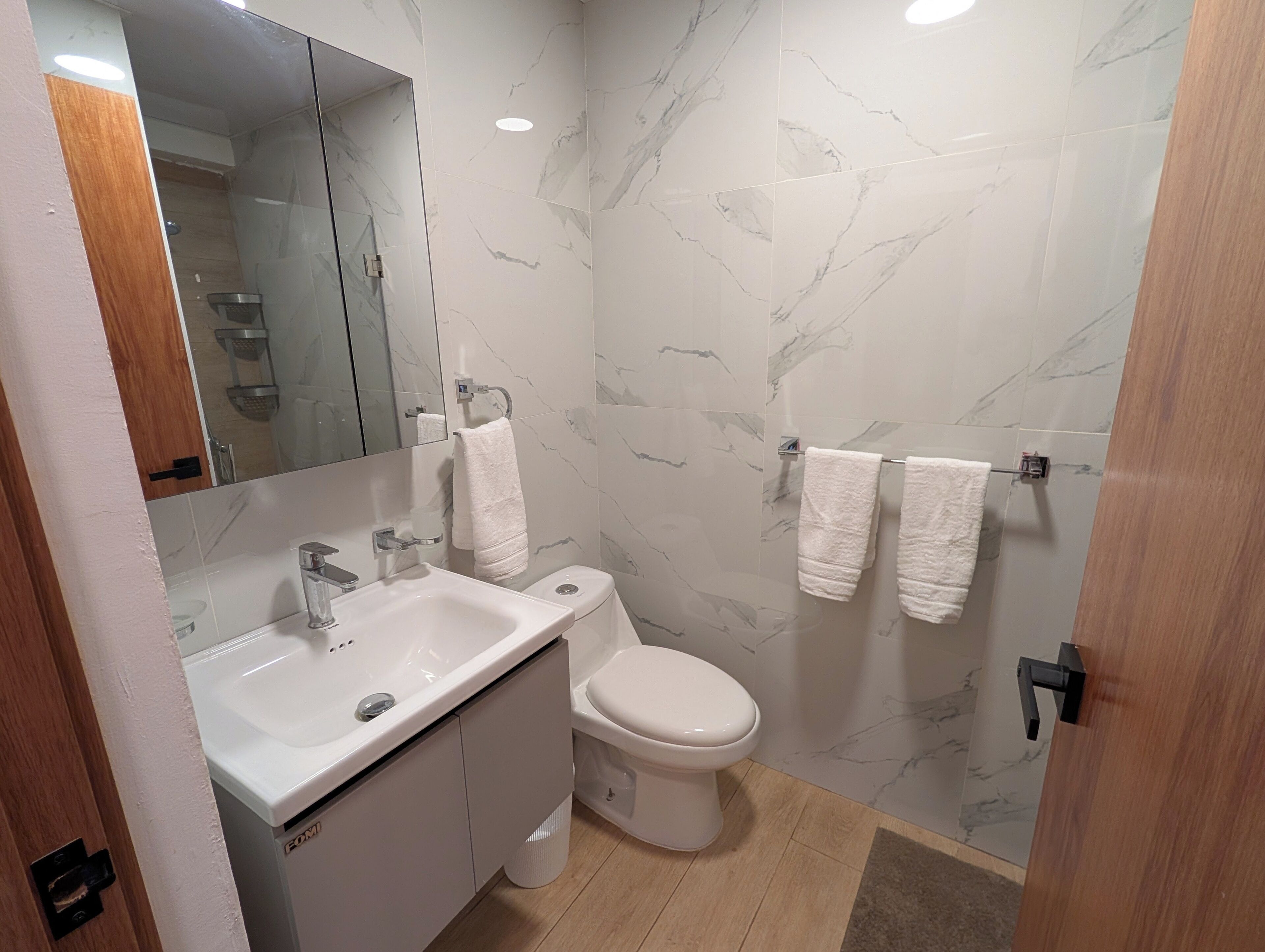 Un bagno moderno con lavandino bianco, servizi igienici e pareti con decoro marmorizzato.
