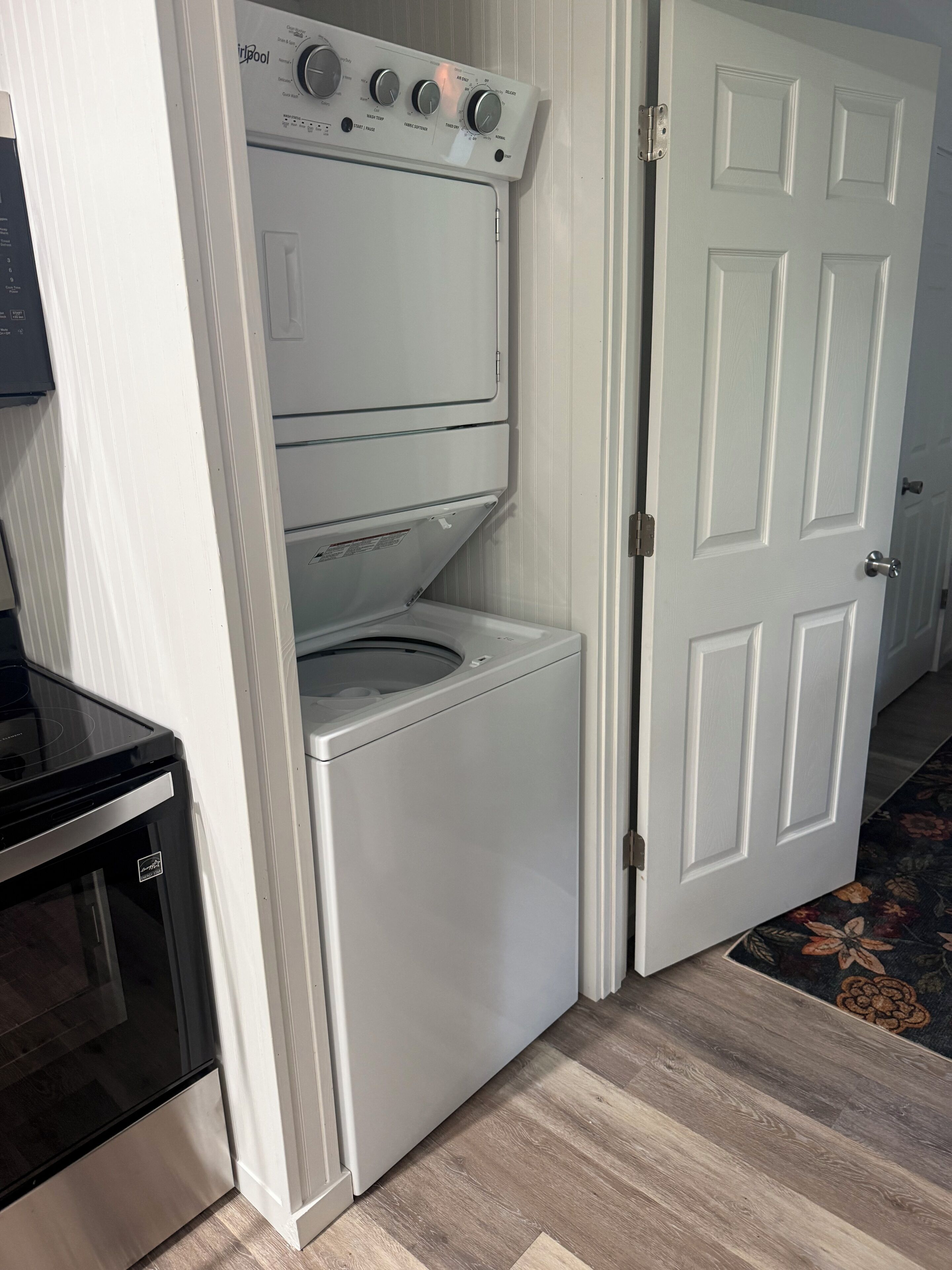 A compact laundry area with a washer and dryer, a stove, and a white door.