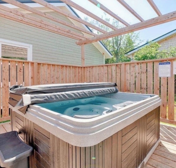 A hot tub in a wooden deck area with a pergola overhead.
