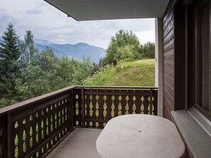 A balcony with a view of a mountainous landscape, a wooden railing, and a small table. - Gadastatt, Obersaxen-Valata, (Surcuolm), 38041B by Interhome (Obersaxen Surcuolm)