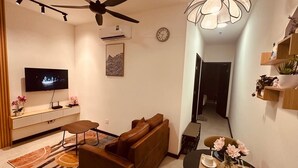 A modern living room with a sofa, a dining table set for two, a television, and a ceiling fan. - Cozy 2-bedroom apartment near KLCC, TRX, Gleneagles Hospital (Kuala Lumpur)