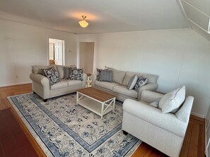 Ein Wohnzimmer mit zwei Sofas, einem Couchtisch und einem gemusterten Teppich.