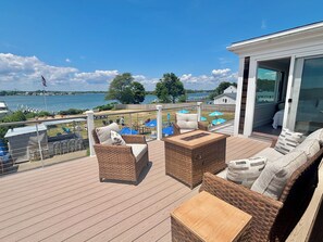 A deck with wicker furniture, a small table, and a view of the water. - Year round 1-bedroom coastal LOFT, sleeps 6, in charming Portsmouth RI (Portsmouth)