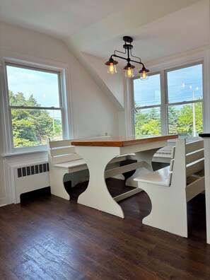 A room with a white table and benches, large windows, and a ceiling light fixture. - Year round 1-bedroom coastal LOFT, sleeps 6, in charming Portsmouth RI (Portsmouth)
