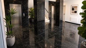 Een moderne lobby met marmeren vloer, een receptiebalie en een trap.