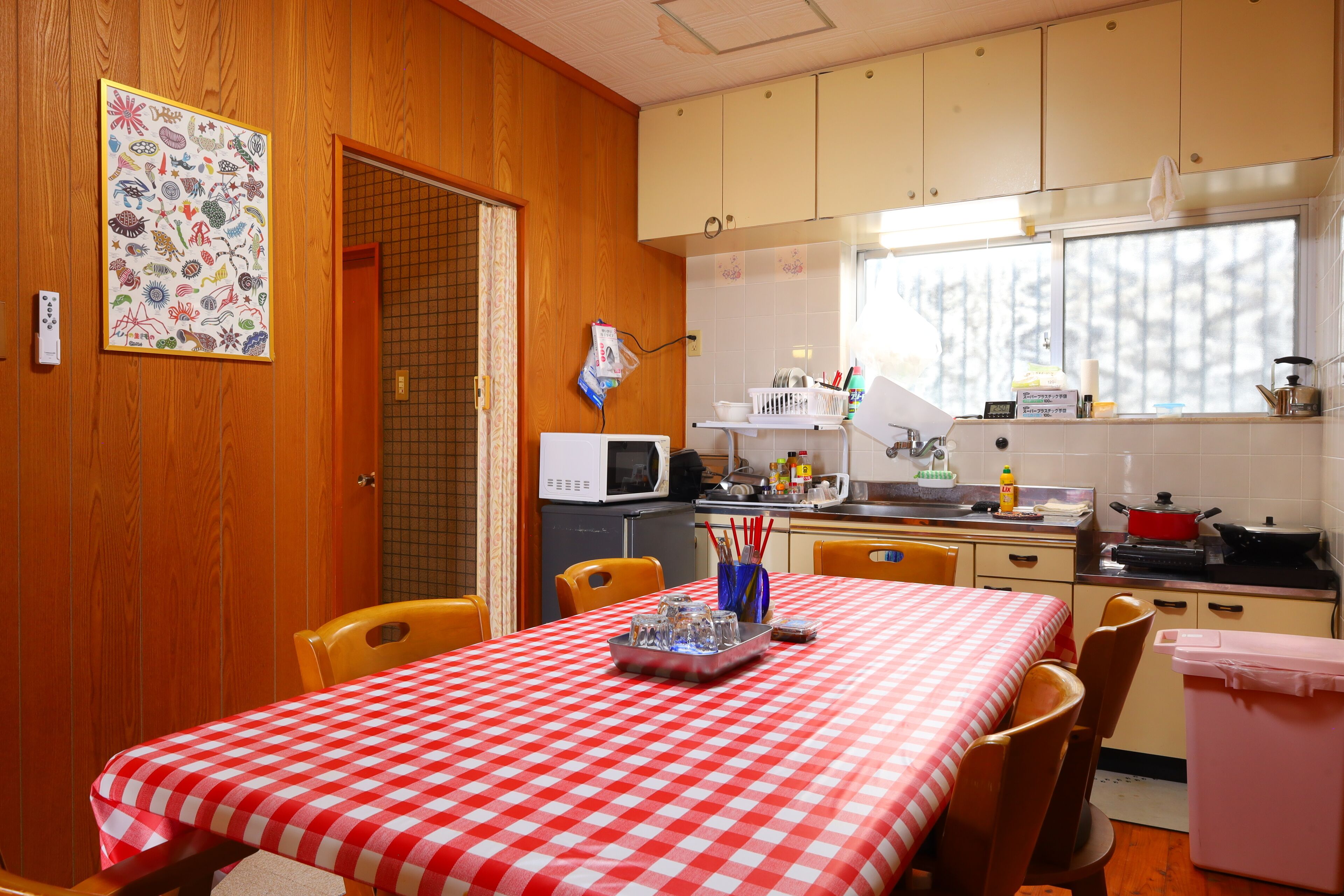 Una cocina con armarios de madera, microondas y una mesa de comedor con mantel a cuadros.