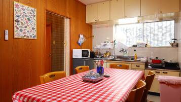 Una cocina con armarios de madera, microondas y una mesa de comedor con mantel a cuadros.