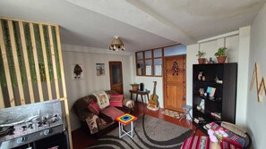 A cozy living room with a sofa, a small table, a guitar, and a bookshelf. - Charming 1-bedroom apartment in the heart of Cusco (Cusco)