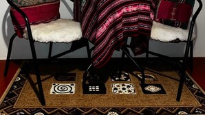A room with a dining table, two chairs, a decorative rug, and a wall-mounted geometric design. - Charming 1-bedroom apartment in the heart of Cusco (Cusco)