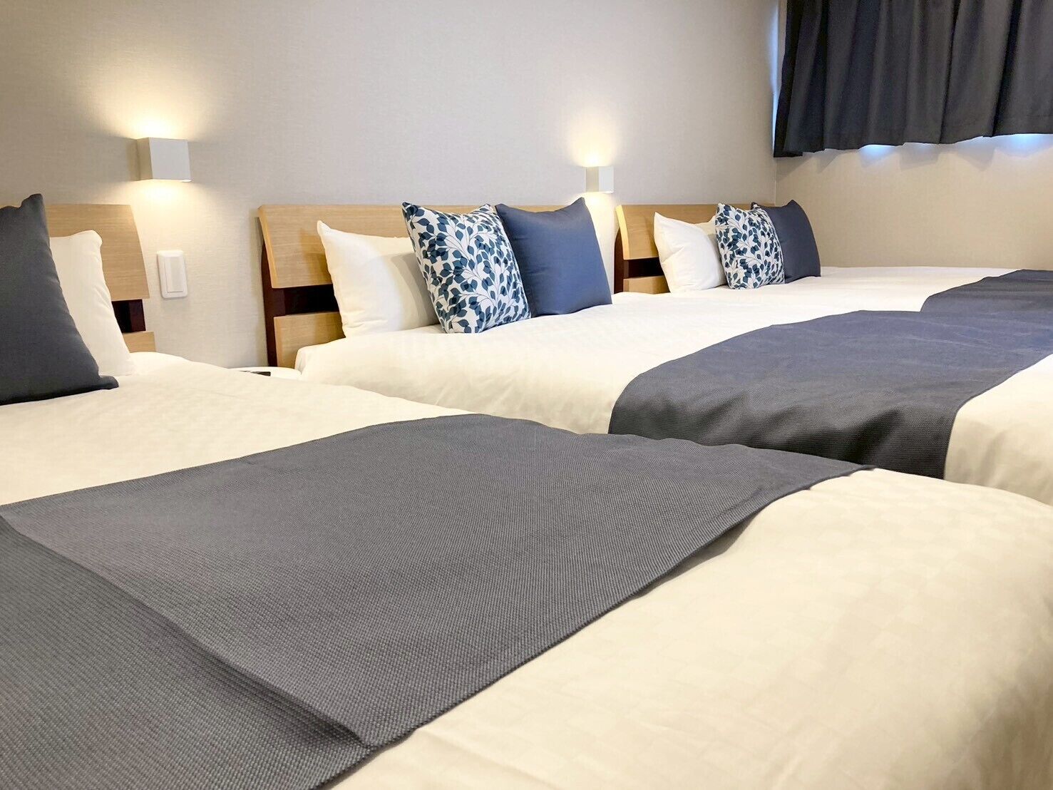 Two beds with headboards, bedside tables, and wall-mounted lamps in a hotel room.