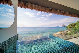 A glass infinity pool with a view of the sea and distant mountains.