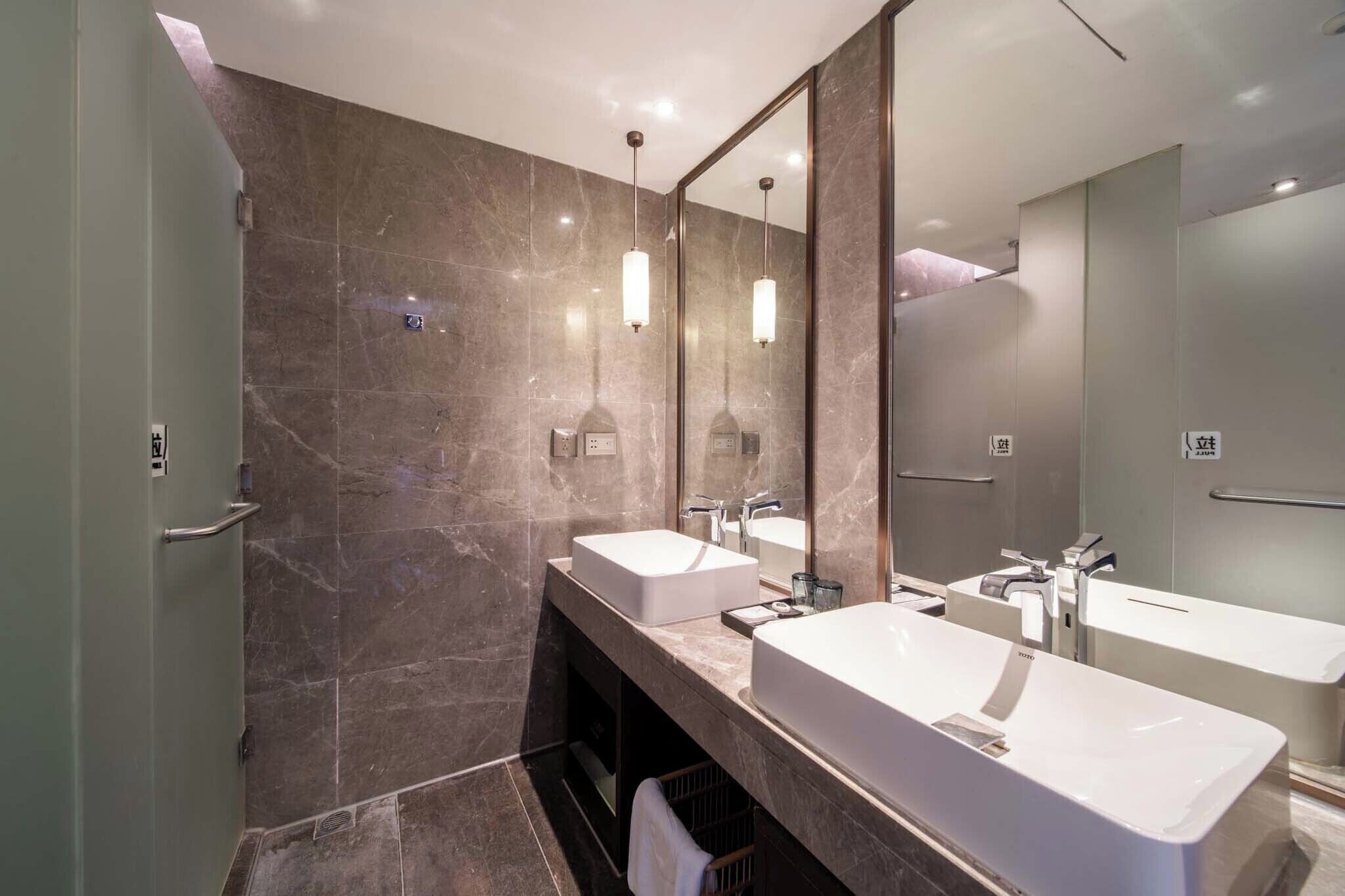 Un baño moderno con dos lavamanos, un espejo grande y una zona de ducha.