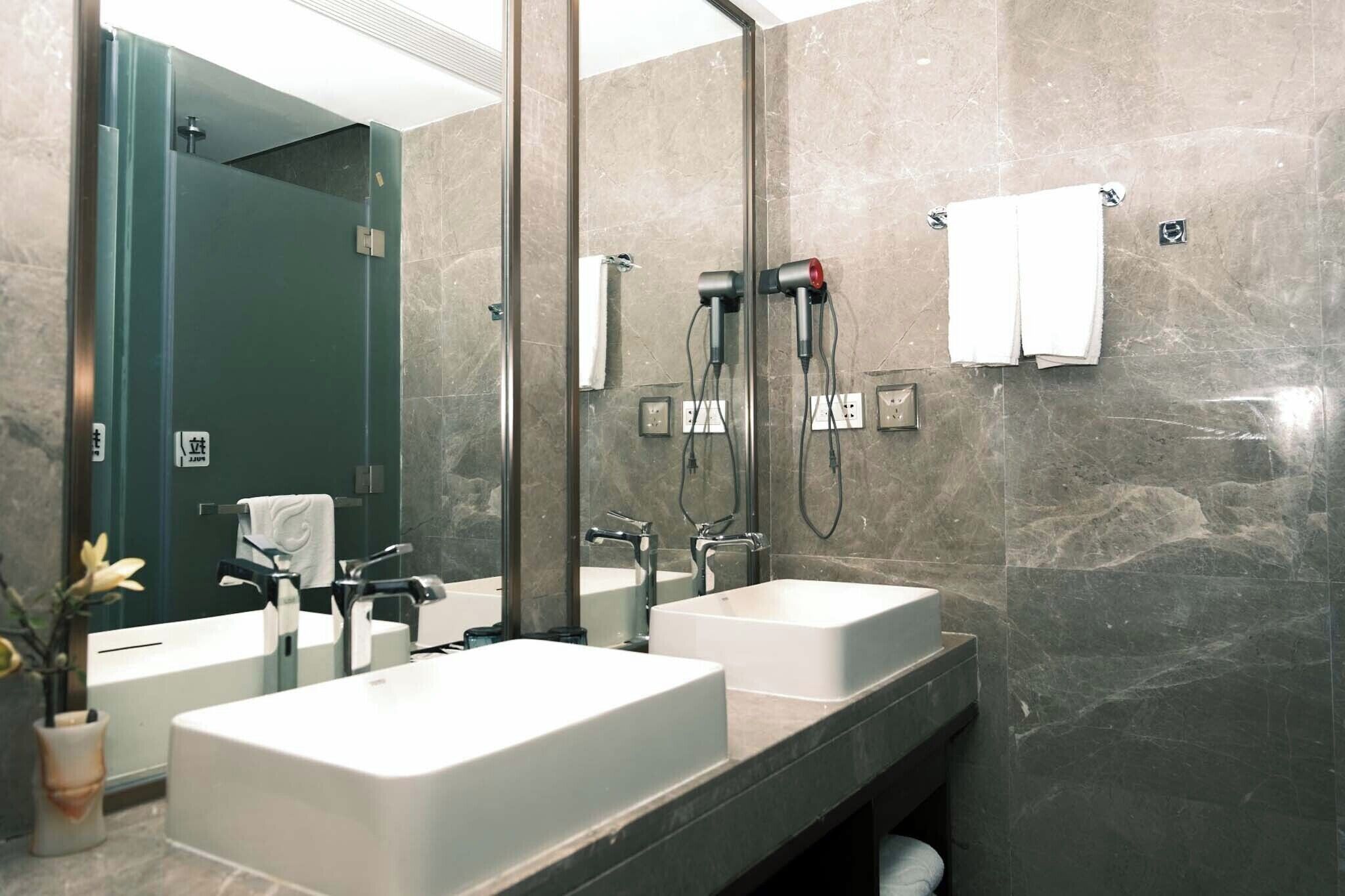 A modern bathroom with two sinks, a large mirror, and a towel rack.