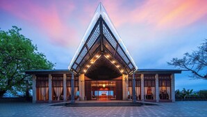 Un hotel moderno con fachada triangular, ventanas amplias y una entrada bien iluminada.