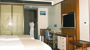 Una habitación de hotel con cama, escritorio, silla, televisión y armario.