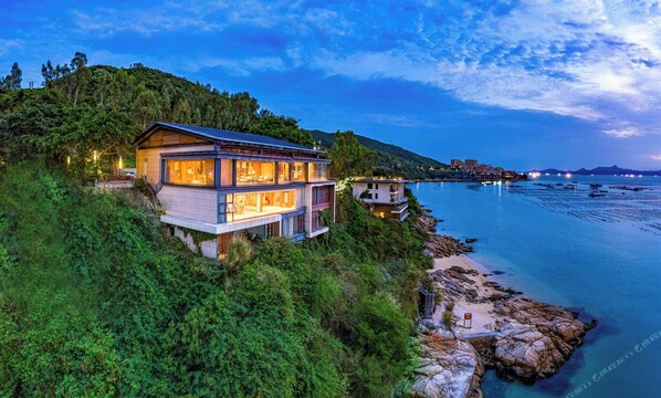 Una casa moderna de dos pisos con balcón con vistas a la costa.