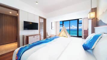 Ein modernes Hotelzimmer mit einem großen Bett, einem Fernseher, einem Kleiderschrank und Blick auf das Meer.