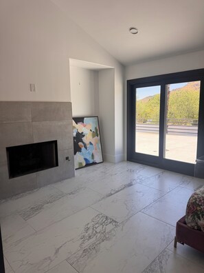 A spacious room with a fireplace, a large abstract painting, and a view through a sliding glass door. - Spacious and beautifully appointed designer 7-bedroom house in Paradise Valley (Paradise Valley)