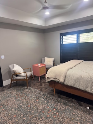 A bedroom with a bed, two chairs, a small table, a ceiling fan, and a window with blinds. - Spacious and beautifully appointed designer 7-bedroom house in Paradise Valley (Paradise Valley)
