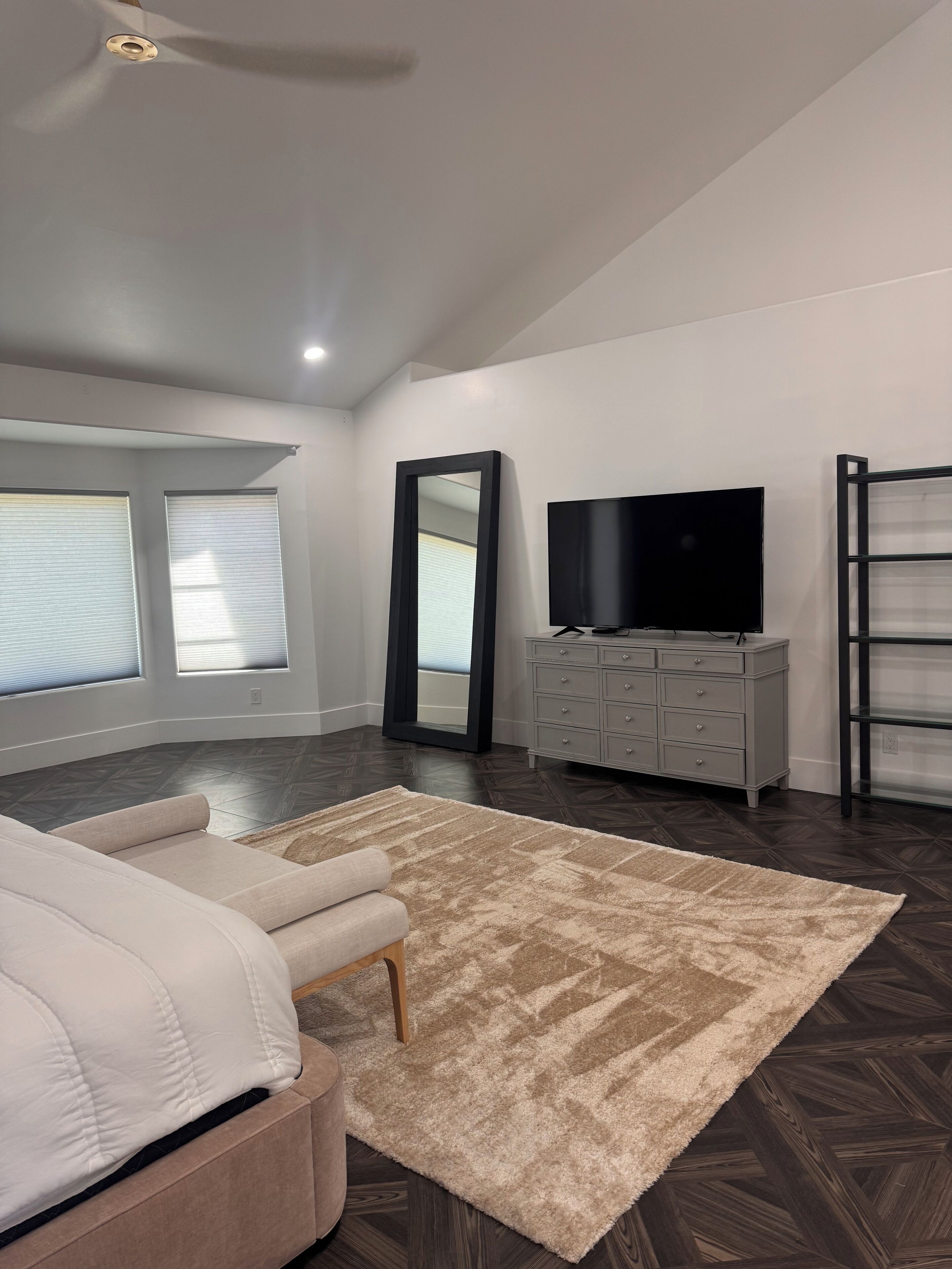 A bedroom with a bed, a dresser, a TV, and a large mirror.