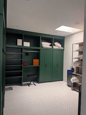 A room with a green wardrobe, shelves with boxes labeled 'GUCCI' and 'LOUIS VUITTON,' a small table, and a herringbone-patterned floor. - Spacious and beautifully appointed designer 7-bedroom house in Paradise Valley (Paradise Valley)