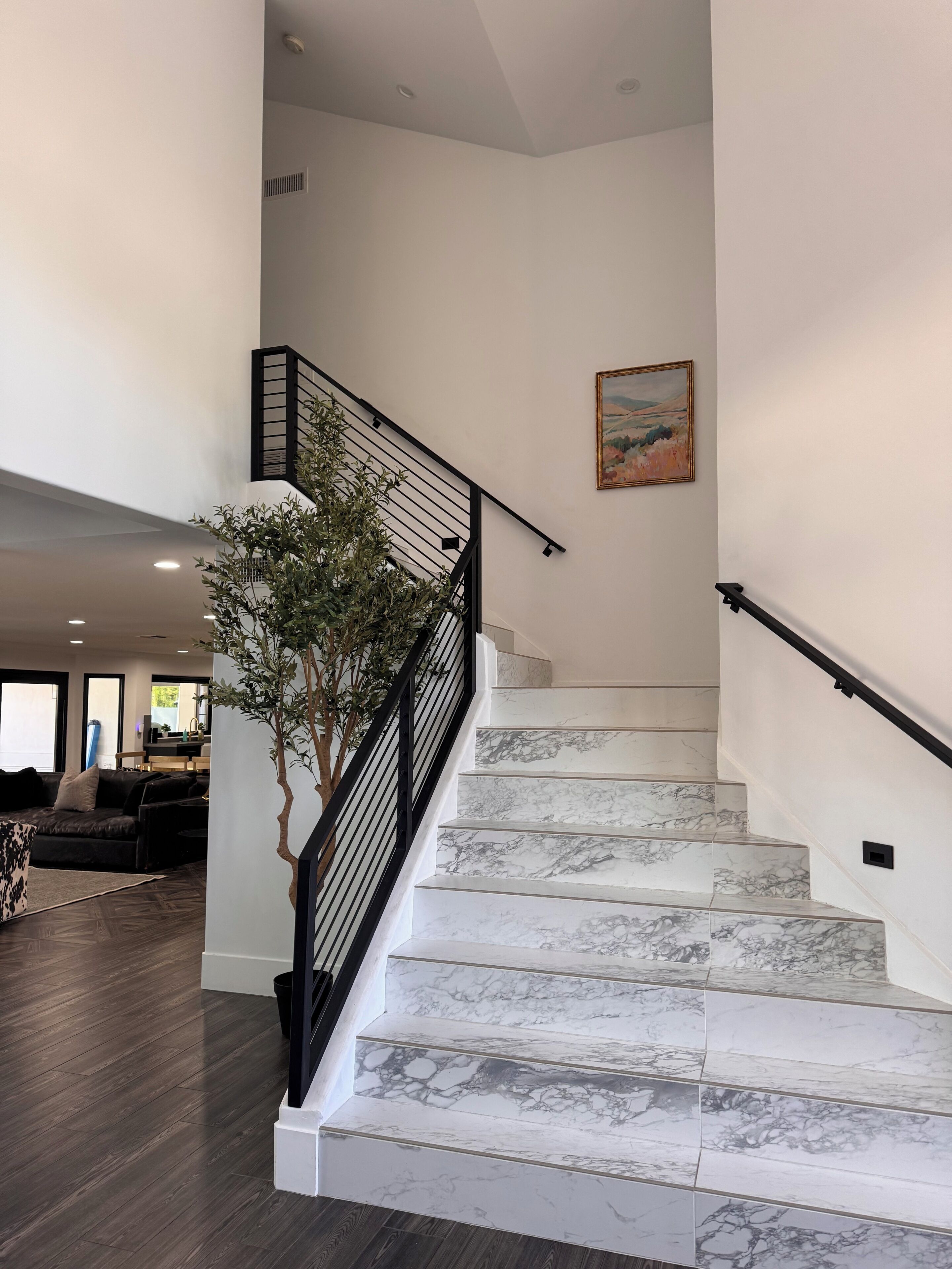 A staircase with marble steps and a black railing, leading to an upper floor.