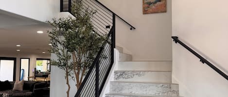 A staircase with marble steps and a black railing, leading to an upper floor.