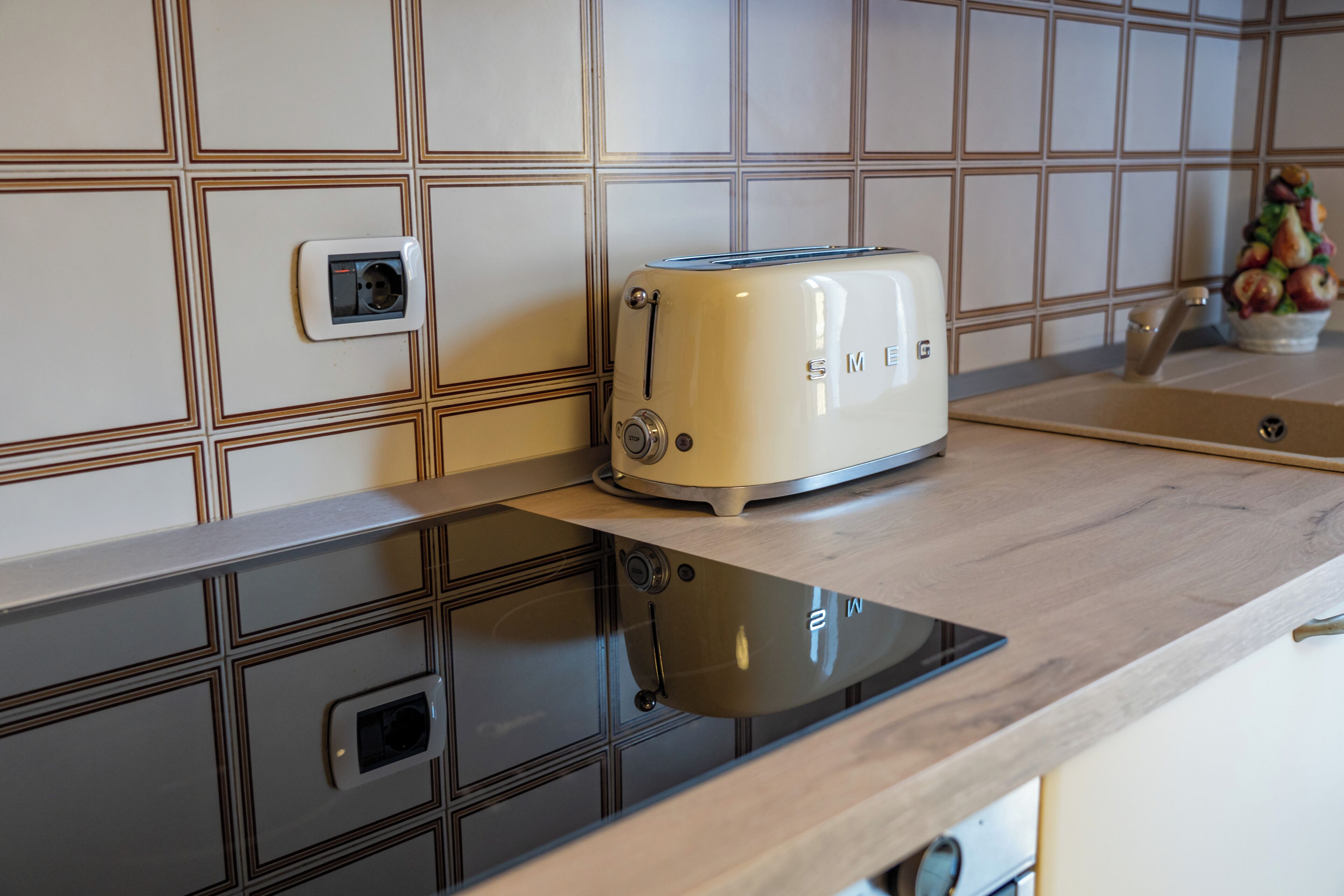 Una cocina con un tostador antiguo sobre una encimera, un enchufe de pared y un frutero.