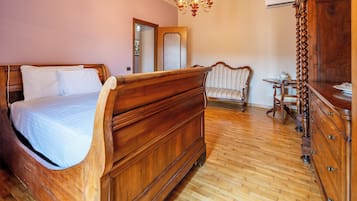 A bedroom with a wooden bed, a chair, a dresser, and a chandelier.
