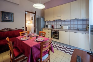 A dining area with a table set for four, a refrigerator, microwave, toaster, and oven in the adjacent kitchen. - Dimora Berzia - Two Bedroom Apartment, Sleeps 2 (Alba)