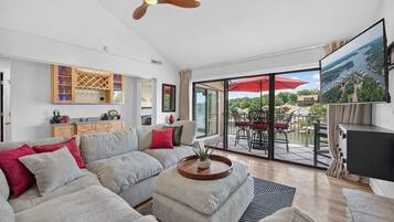 Un salon moderne avec un canapé, une table basse, un téléviseur et un balcon offrant une vue agréable.