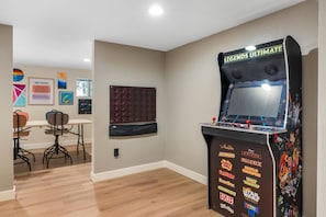 Una habitación con una máquina de pinball, una mesa con sillas y obras de arte en las paredes.