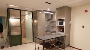 A compact kitchen with a dining area, a microwave, and a stainless steel range hood. - GITE Hotel Yeosu (Yeosu)