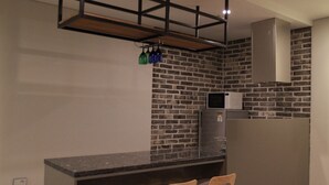 A modern kitchen with a brick wall, a wooden bar counter, and a stainless steel refrigerator. - GITE Hotel Yeosu (Yeosu)