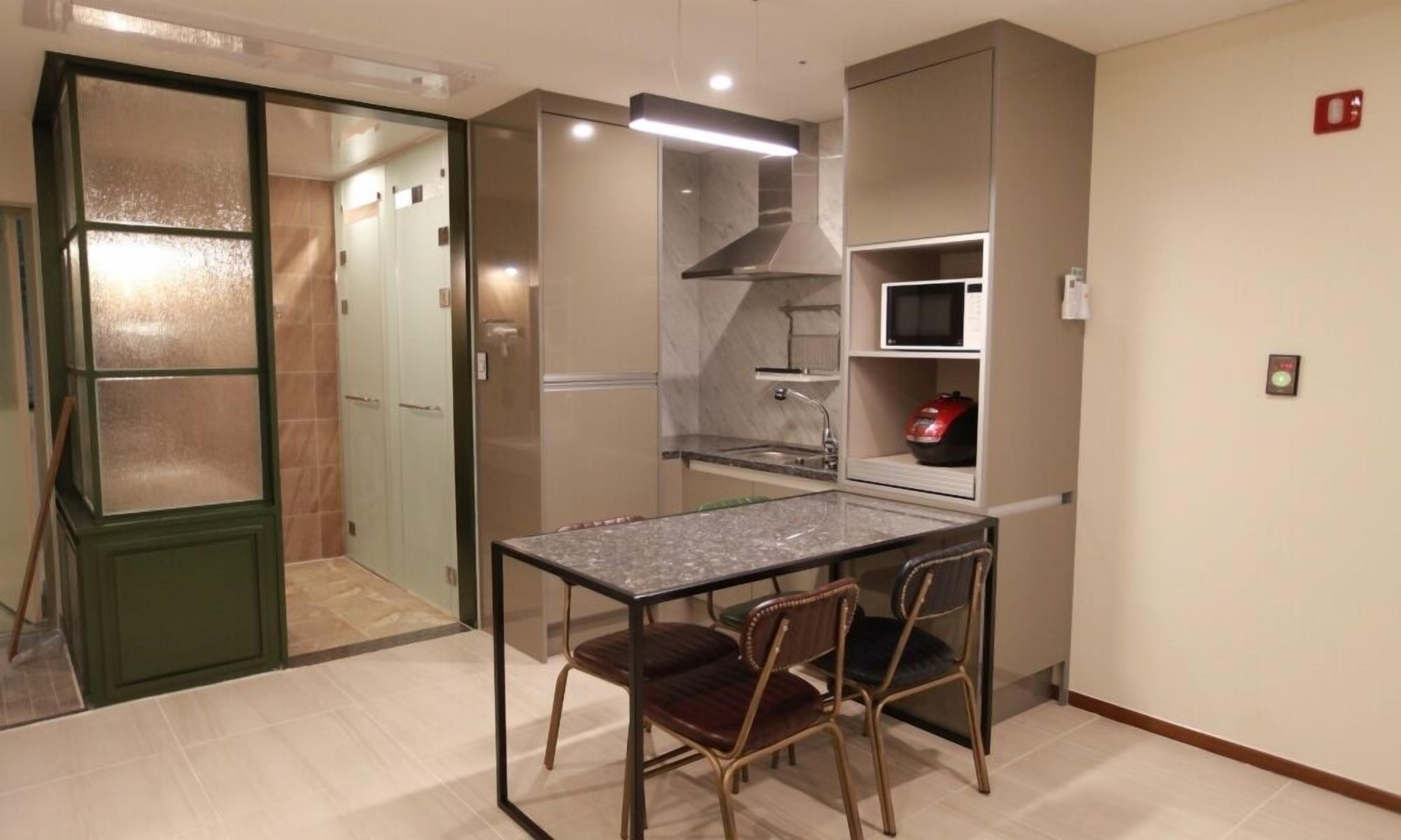 A compact kitchen with a dining table and chairs, a microwave, and a stove.