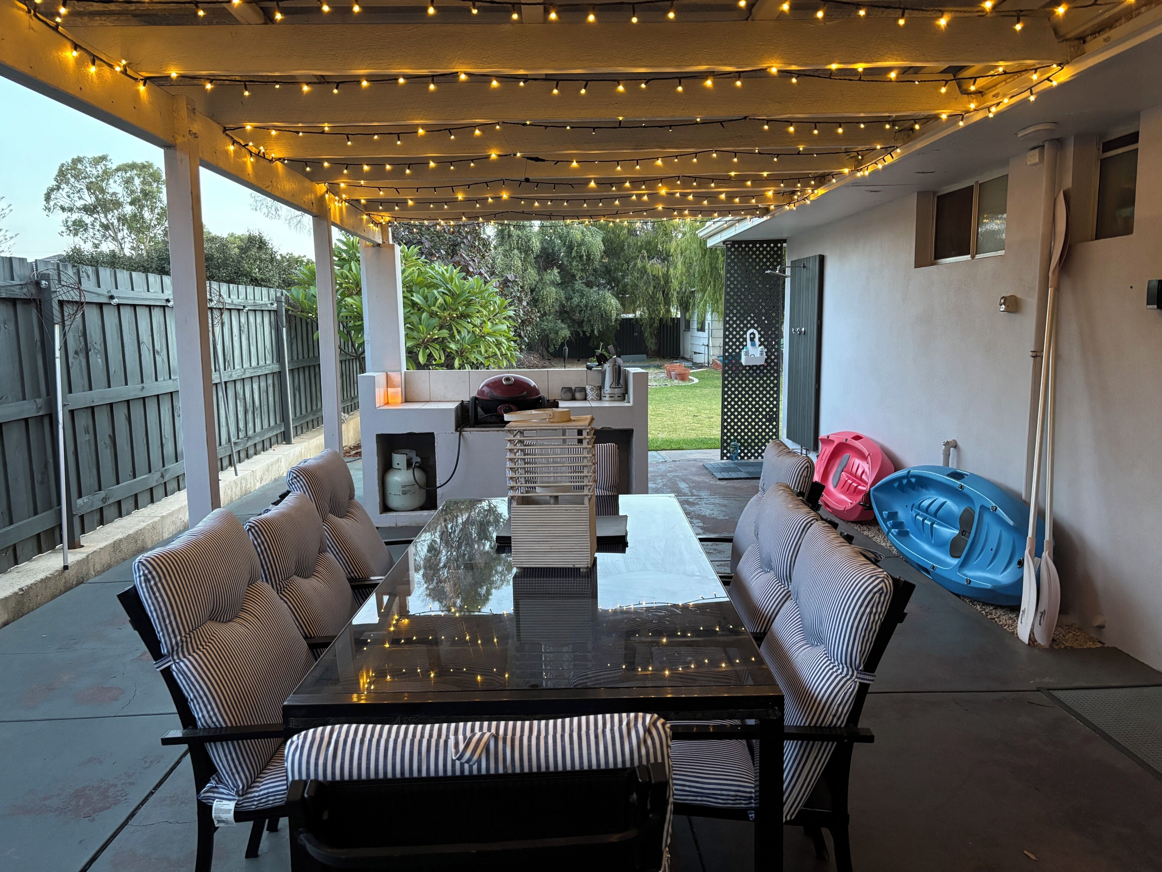 An outdoor patio with string lights, a grill, and seating.