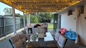 Eine Terrasse im Freien mit Lichterketten, einem Grill und Sitzgelegenheiten.