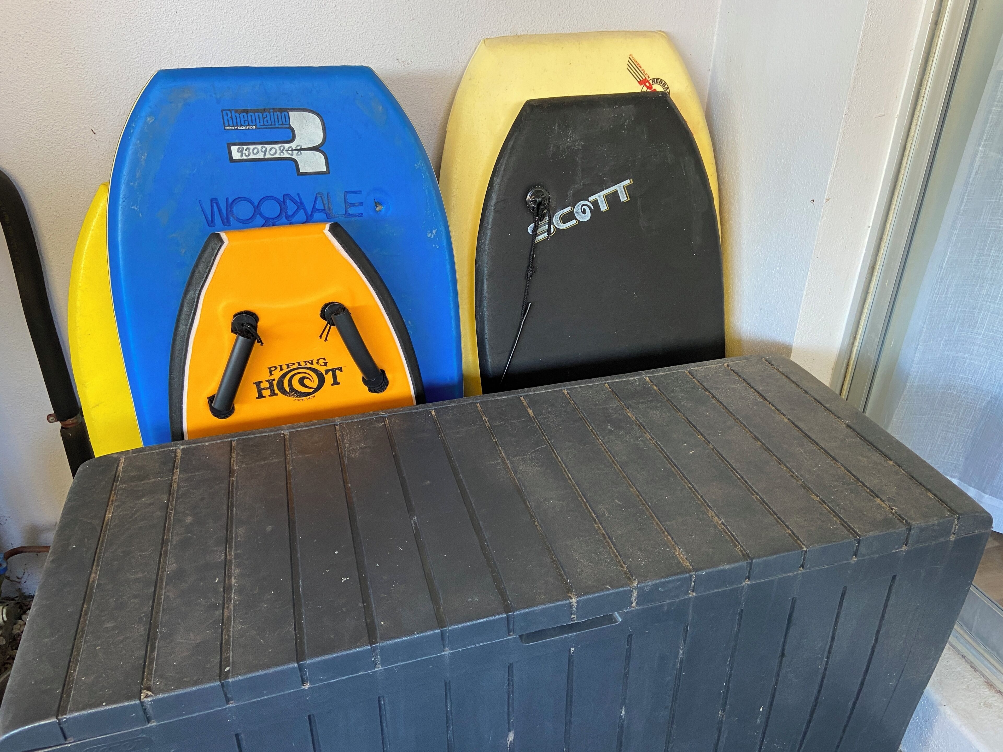 A table with surfboards against a wall.
