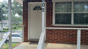 A residential house with a brick facade, a white door, and a window.