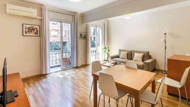 Ein modernes Wohnzimmer mit Essbereich, einer Couch, einem Fernseher und einem Balkon mit Topfpflanze.