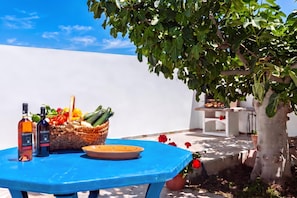 Une table bleue avec des bouteilles, un panier de légumes et une assiette.