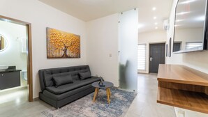 A modern living room with a sofa, a small table, and a painting on the wall.