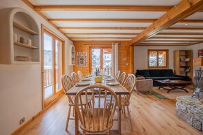 A dining area with a wooden table and chairs, a sofa, and a fireplace. - Chalet Skyline Mont Blanc, Servoz (Chamonix), France (Servoz (Chamonix))