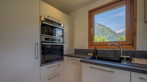 Eine Küche mit eingebauten Backöfen, einem Spülbecken und einem Fenster mit Blick auf die Berge.