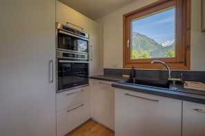 Eine Küche mit eingebauten Backöfen, einem Spülbecken und einem Fenster mit Blick auf die Berge.