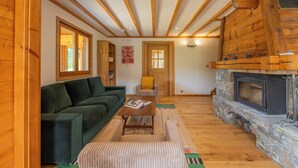 Ein Holzinserior mit einer Couch, einem Tisch, einem Kamin und einer Tür.