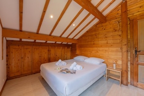 A wooden-paneled room with a bed, towels, and a nightstand. - Chalet Skyline Mont Blanc, Servoz (Chamonix), France (Servoz (Chamonix))